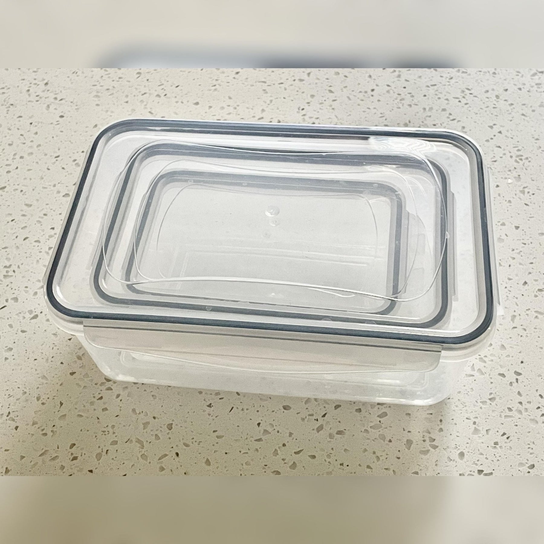 7 of 7: Live Life on Purpose Insulated Lunch Bag Set with Food Containers - Stack of clear plastic containers with black lids on a speckled countertop