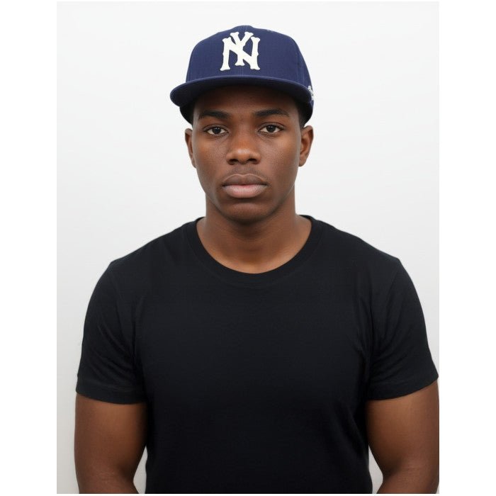 3 of 6: Brooklyn Eagles Heritage Snapback Baseball Cap (Lifestyle) - Man wearing a navy blue cap with a logo and a black t-shirt on a white background