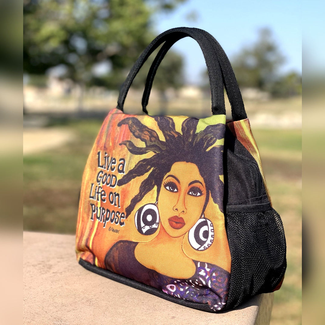 Live Life on Purpose Insulated Lunch Bag Set with Food Containers - Handbag with a colorful design of a woman's face and text, placed outdoors. (Lifestyle2)