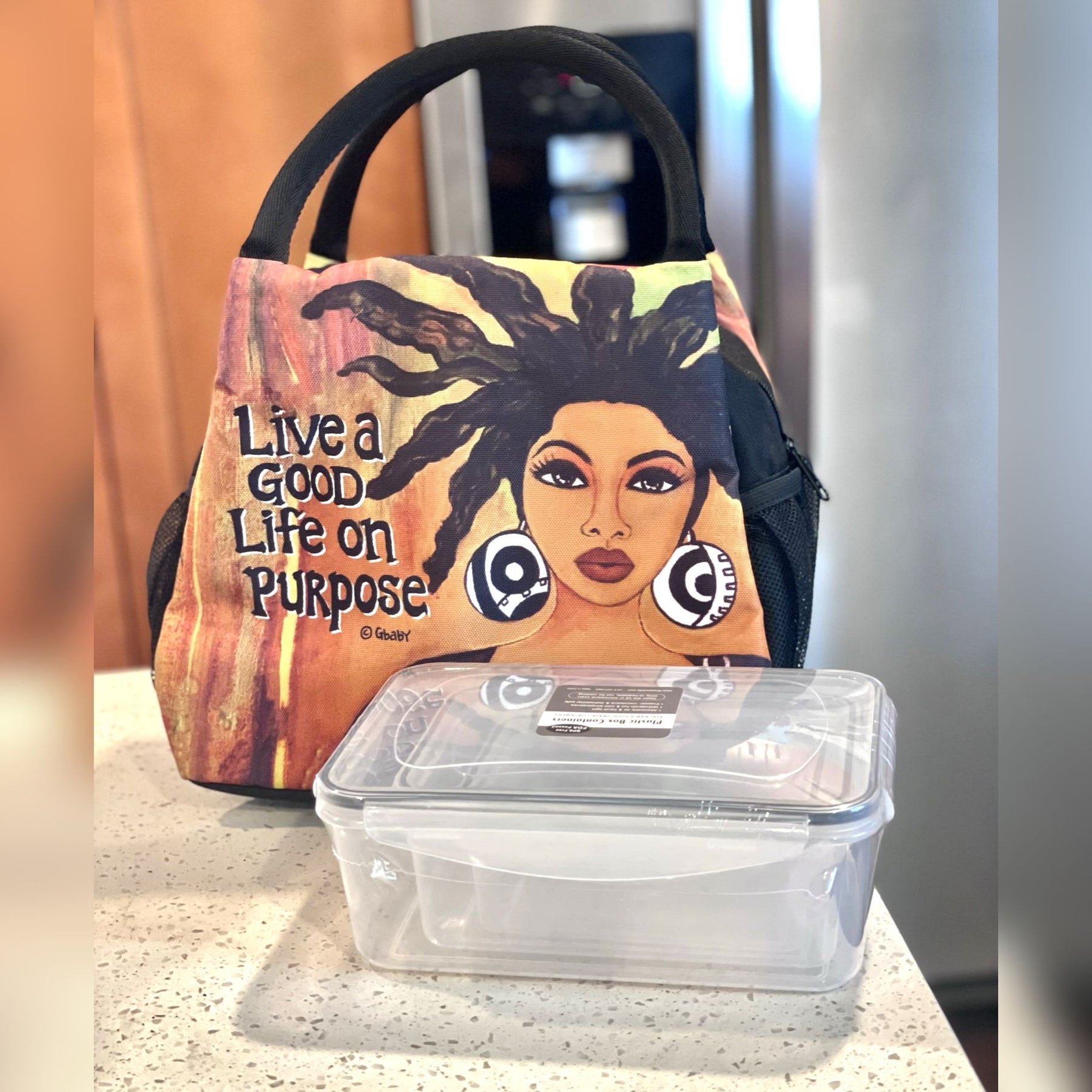 2 of 7: Live Life on Purpose Insulated Lunch Bag Set with Food Containers - Lunch bag with artistic design of a woman and text 'Live a Good Life on Purpose' next to a clear plastic container. (Lifestyle)