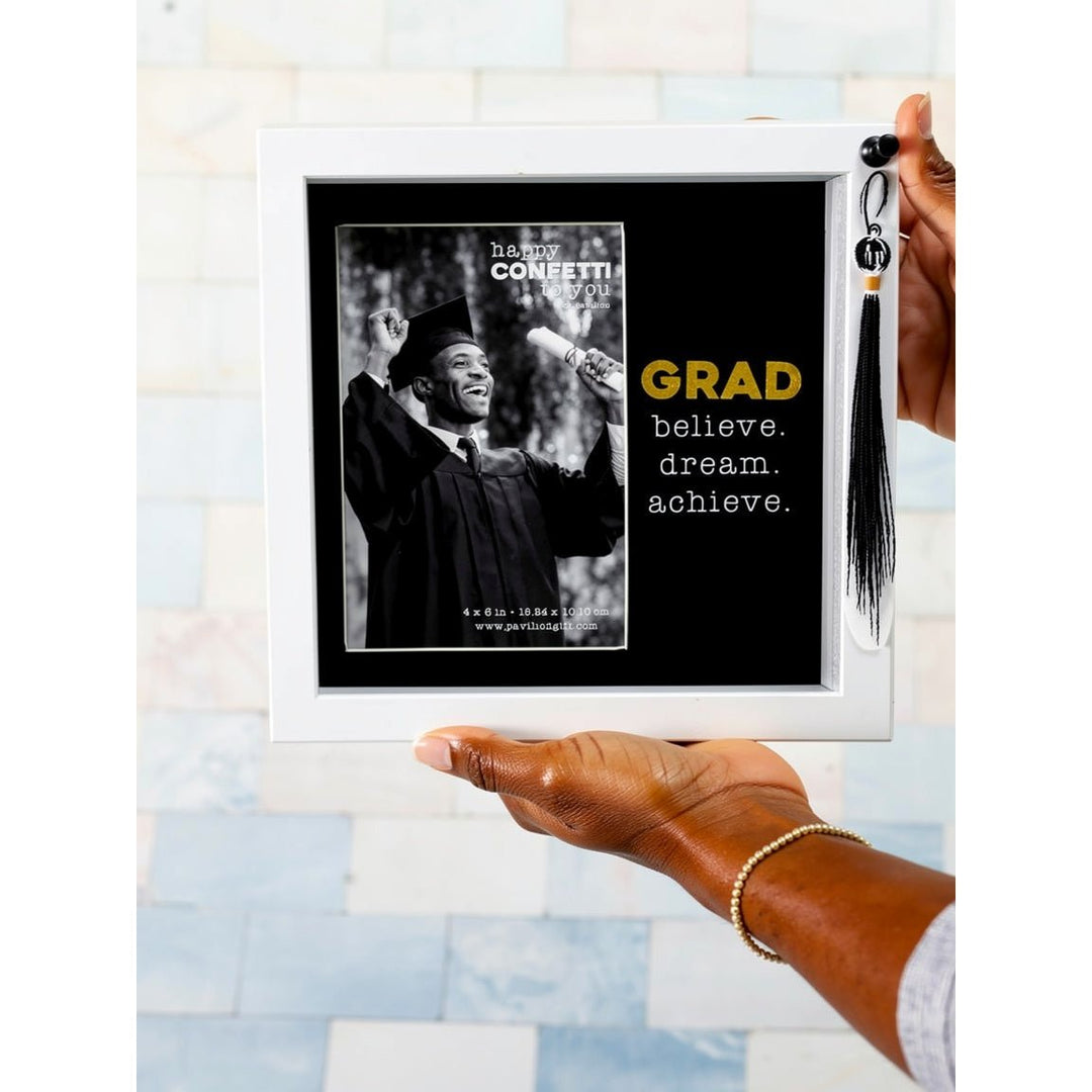 Graduate: Dream, Believe & Achieve Shadow Box Picture Frame w/ Tassel (Lifestyle 3) - Framed graduation photo with motivational quote and tassel, held by a hand.