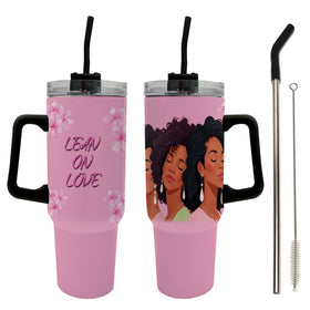 Alpha Kappa Alpha Ivy Love Sisterhood Tumbler with Handle (Main) - Two pink handled tumbler cups with clear lids and black straws are shown on a white background, alongside a metal cleaning brush. The left cup has pink floral graphics and the text 'LEAN ON LOVE', while the right cup features an illustrated portrait of three Black women.