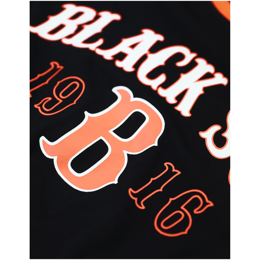 Baltimore Black Sox Long Sleeve T-Shirt (Front Detail) - Close-up of a black garment featuring large orange and white lettering, including the number 8 and partial text reading BLACK and 16.
