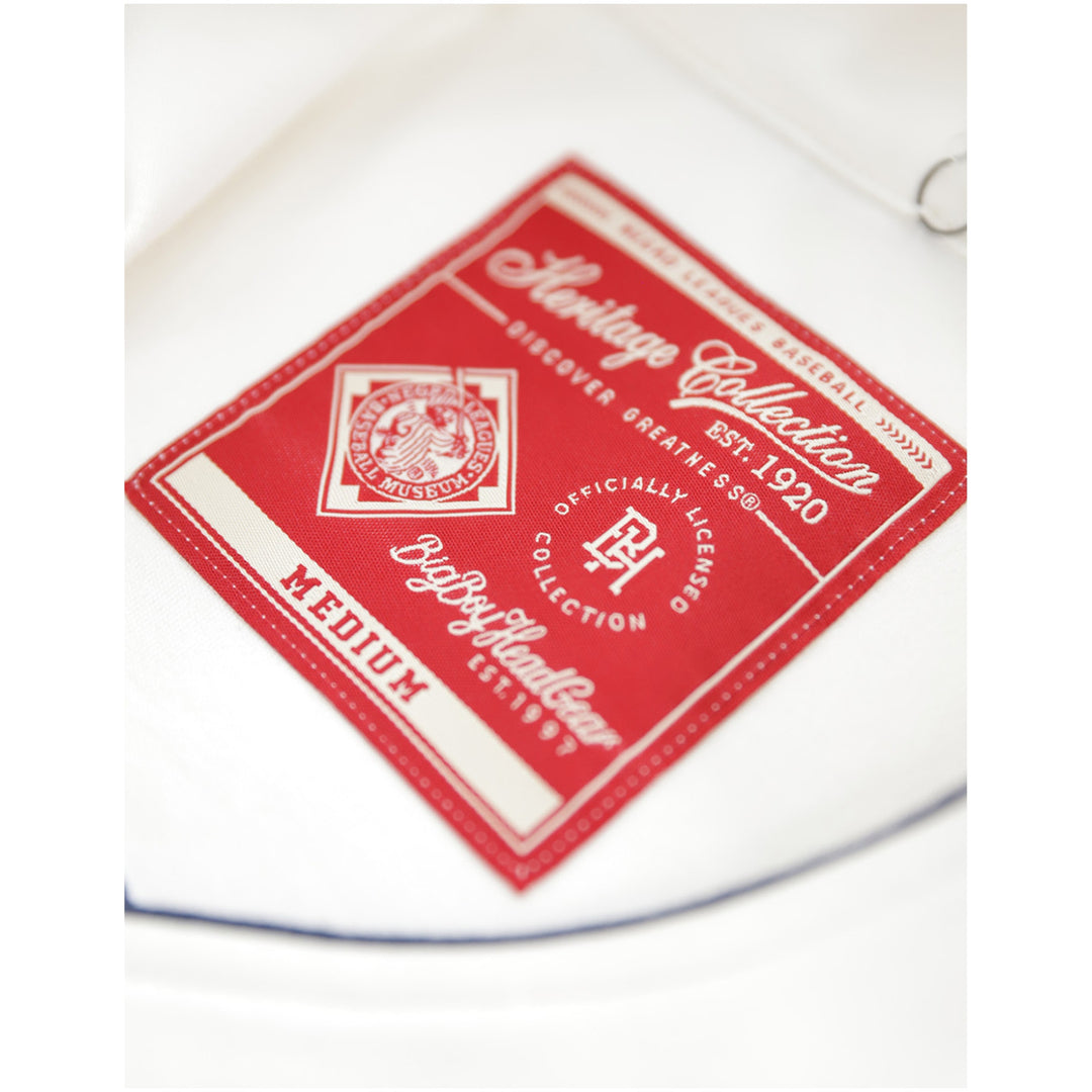 Baltimore Black Sox Negro Leagues Heritage Baseball Jersey (Front Detail 3) - A close-up of a red and off-white fabric label reading 'Heritage Collection' and 'Medium', placed on a white textile background.