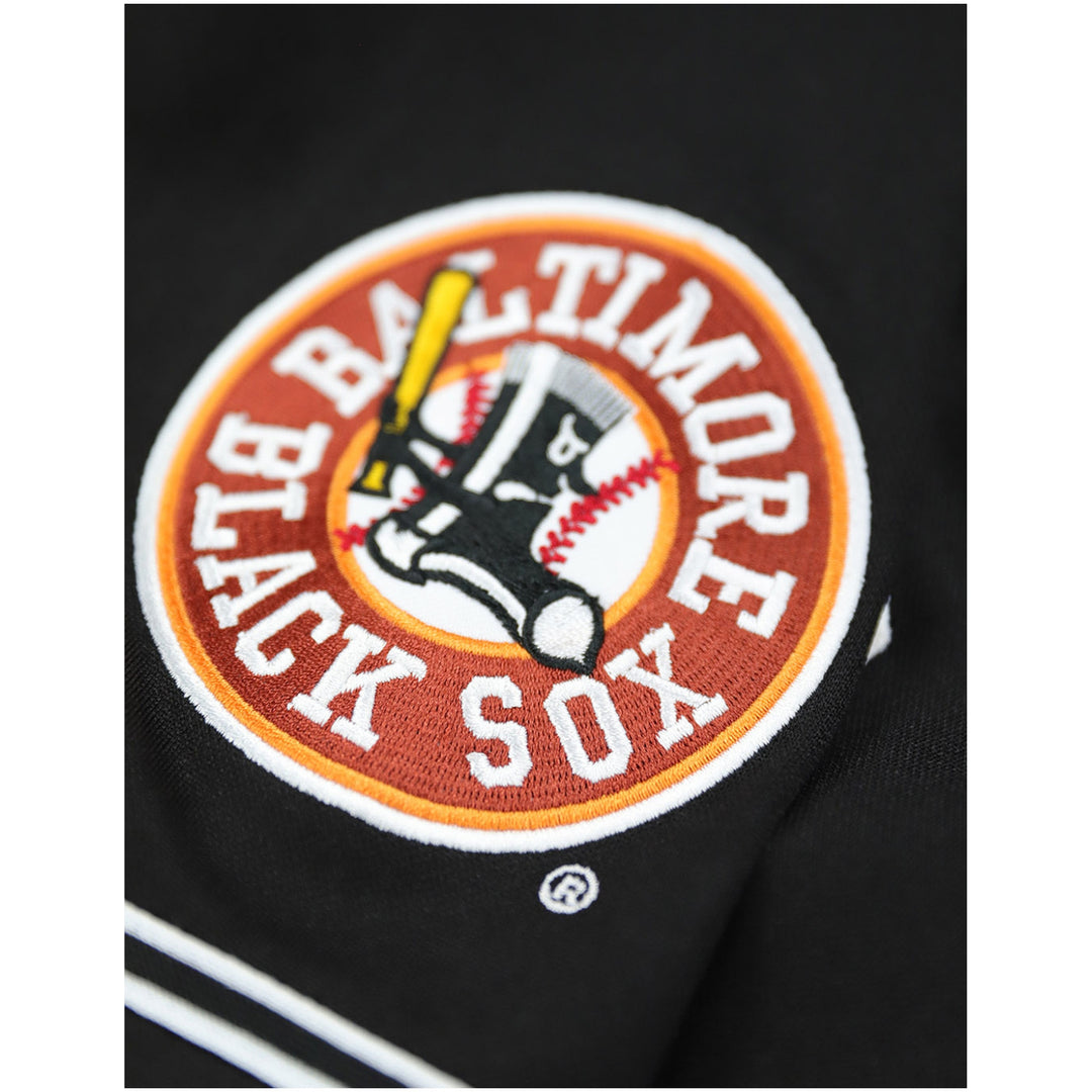 Baltimore Black Sox Legacy Baseball Jersey (Sleeve Detail 2) - Close-up of a Baltimore Black Sox embroidered patch on a black garment, showing the team logo and text.