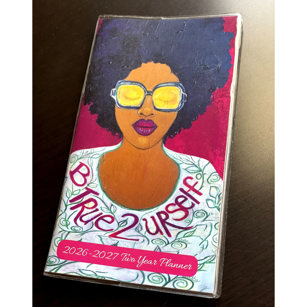 Be True to Yourself: 2026-2027 Two Year Black Art Pocket Planner (Lifestyle Photo) - Planner with a colorful design of a woman's face and 'Be True 2 Yourself' text on a dark surface.