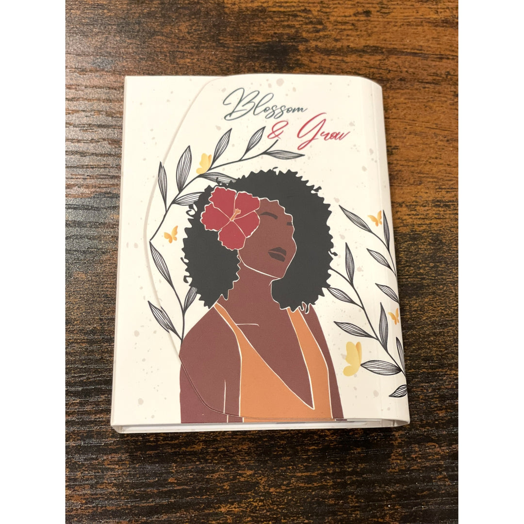 Blossom and Grow: African American Stylus Purse Pal by Janine Robinson (Lifestyle) - Notebook with a design of a woman with a flower in her hair on a wooden surface