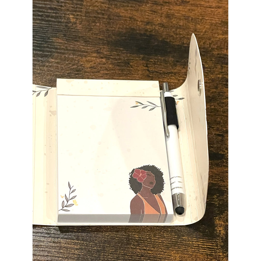 Blossom and Grow: African American Stylus Purse Pal by Janine Robinson (Interior Detail 2) - Notebook with a printed design of a woman with a flower in her hair, accompanied by a pen on a wooden surface.