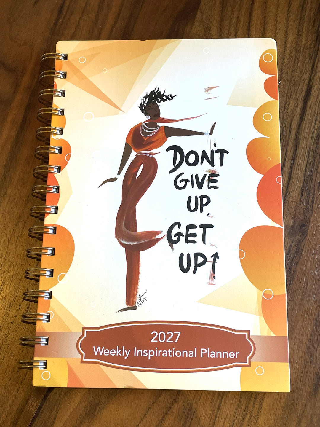Don't give up get up planner cover, Black woman praise dancing. planner flat on wood surface.
