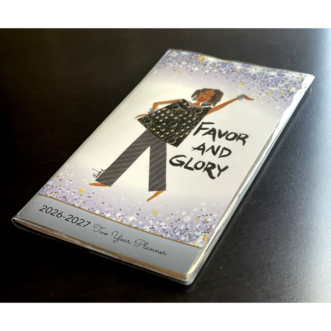 Favor and Glory by Cidne Wallace: 2026-2027 Two Year African American Pocket Calendar (Lifestyle Photo 2) - Planner with illustration of a woman and 'Favor and Glory' text on a dark surface