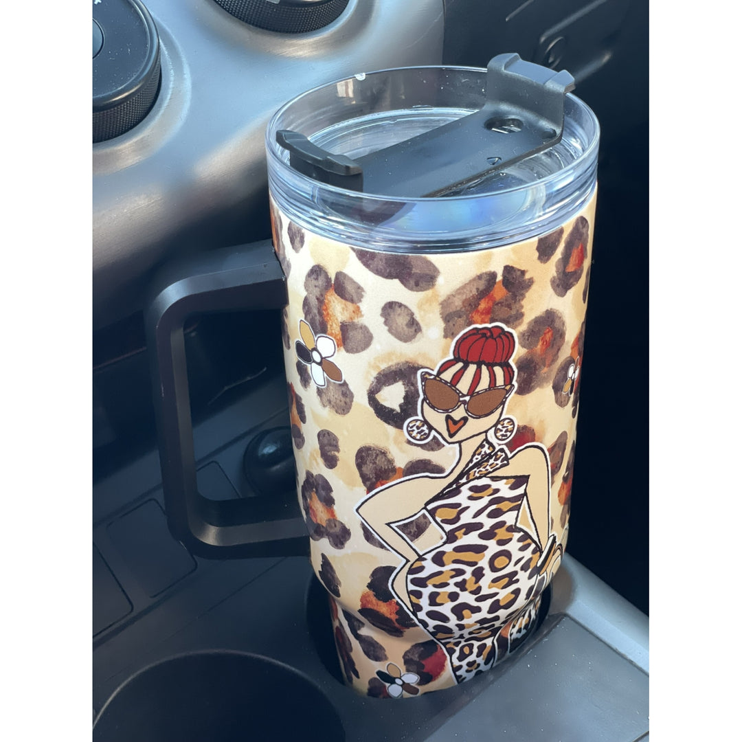 Goddess Vibes by Kiwi McDowell: African American Tumbler with Long Handle (Lifestyle) - A handled travel tumbler with a clear lid and flip-top straw, featuring a beige leopard print background and a stylized illustration of a woman in a leopard-print dress and red hat, shown sitting in a car cup holder.