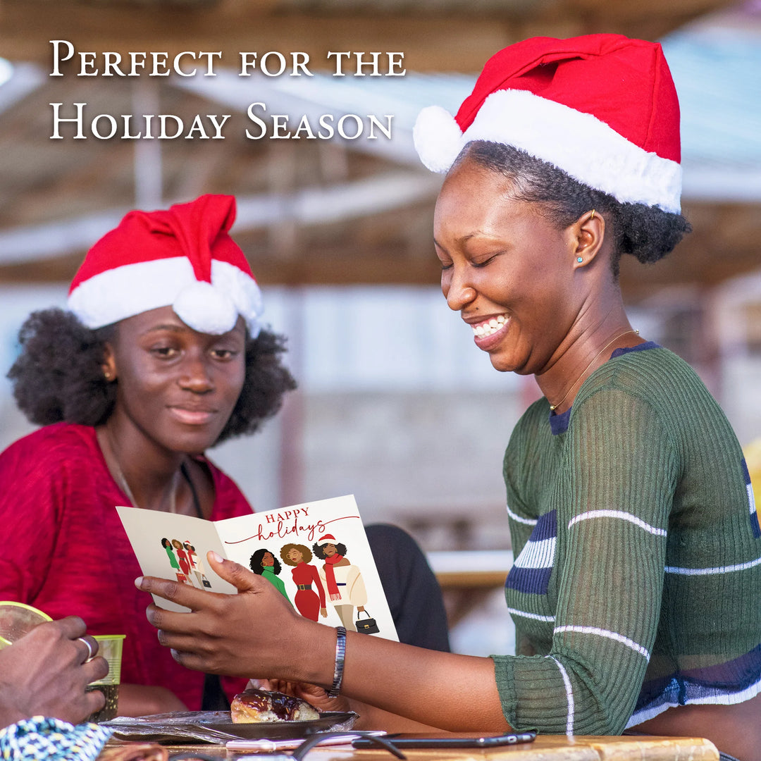 Happy Holidays: African American Christmas Card Box Set (Infographic) - Two women wearing Santa hats, one holding a card with a festive design, in a casual setting.