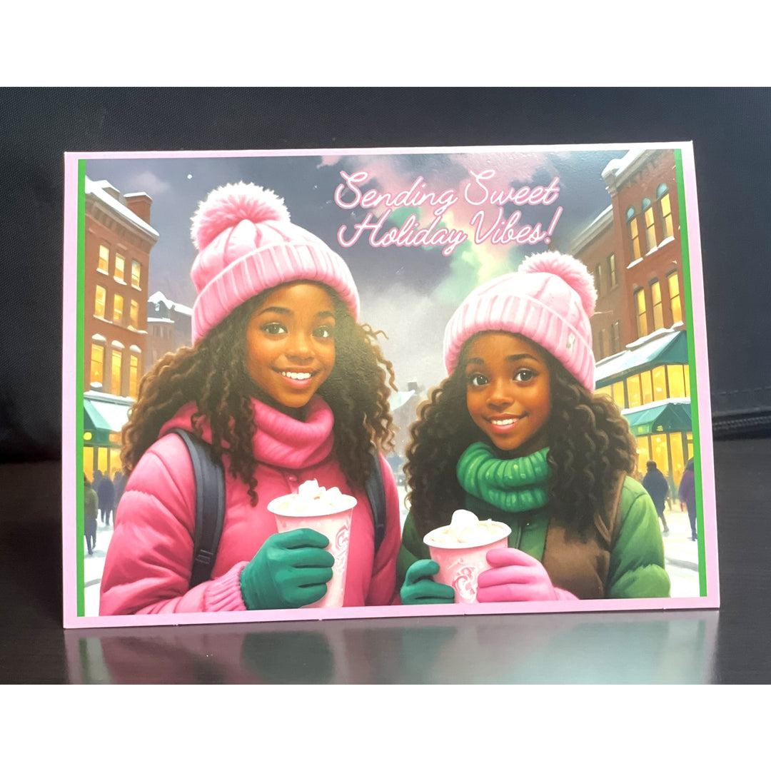 Holiday Vibes (Ivy Edition): African American Christmas Card Box Set (Lifestyle, Exterior) - Holiday card with two people wearing pink hats and scarves, holding hot chocolate, with a snowy street scene in the background.