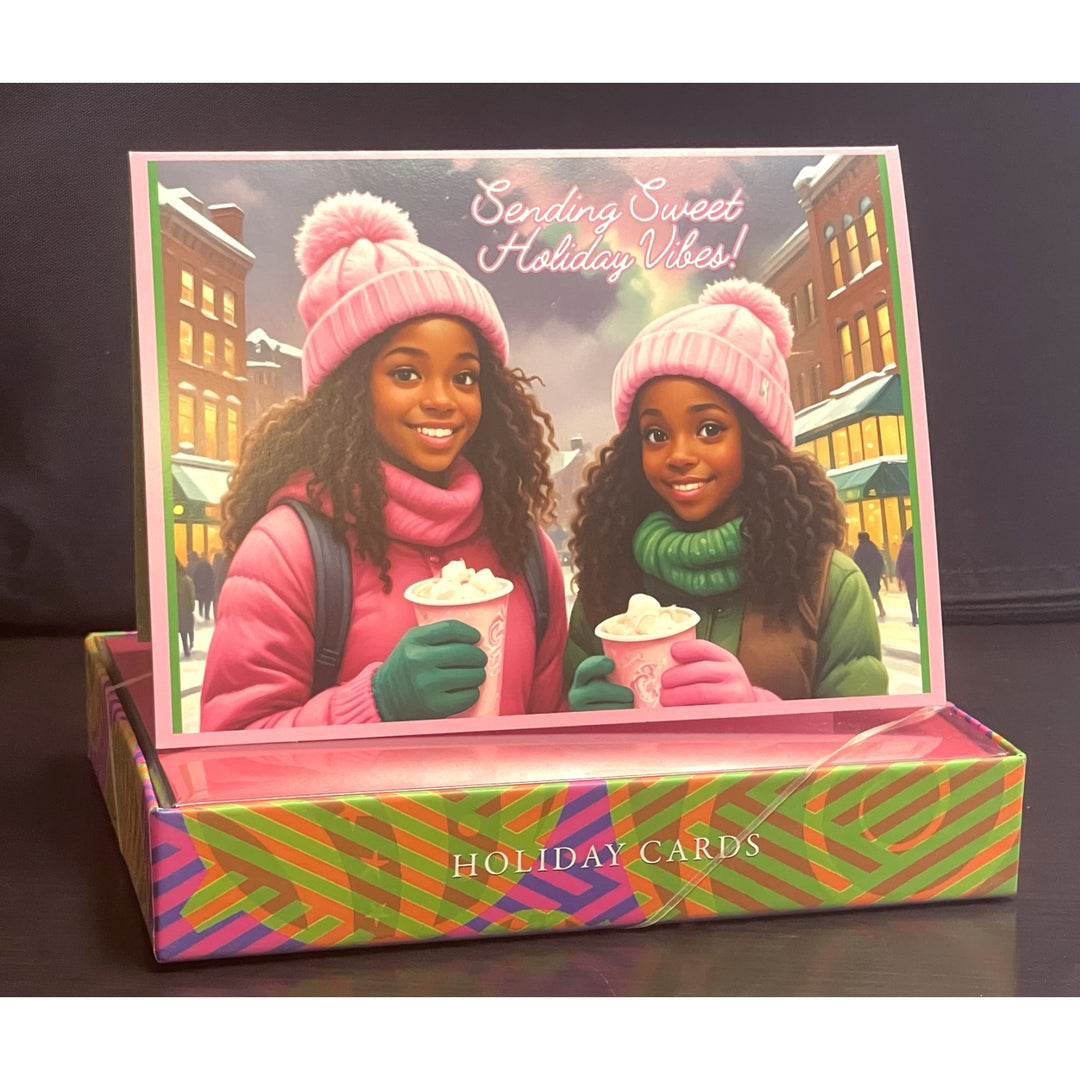 Holiday Vibes (Ivy Edition): African American Christmas Card Box Set (Lifestyle, Full Box) - Box of holiday cards with two girls in winter hats and scarves holding hot chocolate.