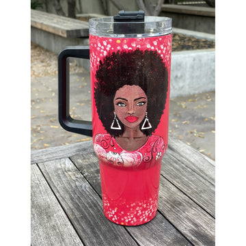 I am Powerful by Sylvia "GBaby" Cohen: Detla Sigma Theta Tumbler with Handle (Lifestyle) - A red insulated travel tumbler with a black handle and lid, featuring a printed illustration of a Black woman with an afro hairstyle, sitting on a wooden table outdoors.