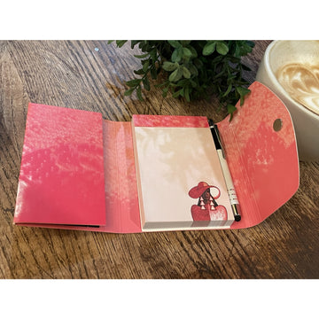Intentionally Me: Detla Sigma Theta Stylus Purse Pal (Interior) - Pink notebook with a pen on a wooden surface next to a cup of coffee and plant
