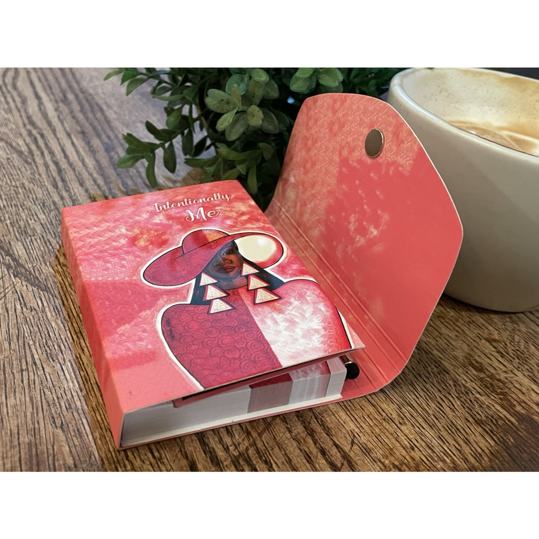 Intentionally Me: Detla Sigma Theta Stylus Purse Pal (Lifestyle) - Pink notebook with a decorative cover on a wooden surface next to a cup of coffee.