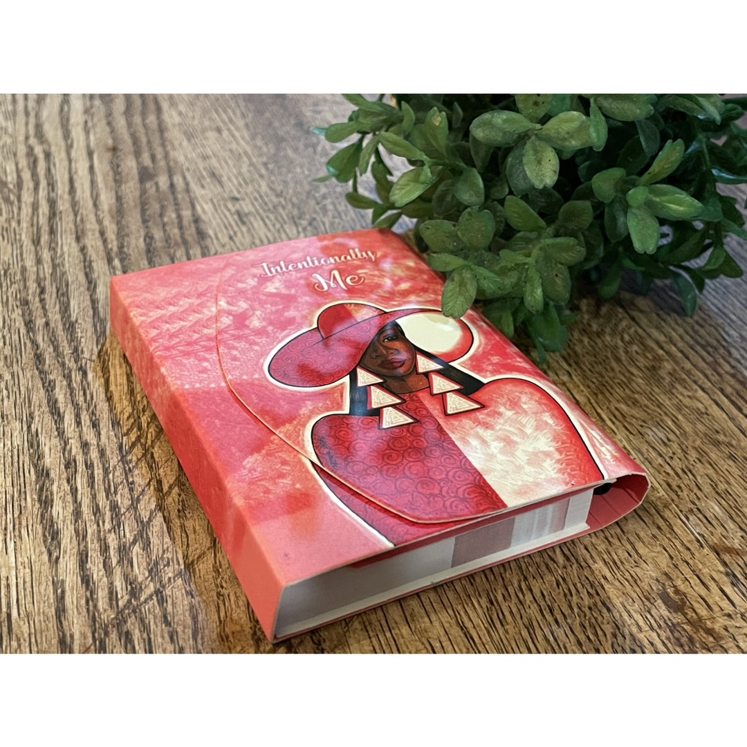 Intentionally Me: Detla Sigma Theta Stylus Purse Pal (Lifestyle 2) - Pink book with a heart design on a wooden surface with a plant in the background