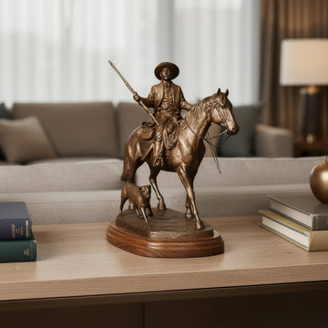 Into the Territory: Bass Reeves Sculpture by Harold Holden (Lifestyle) - Bronze statue of a man on horseback with a dog on a wooden table in a living room setting.