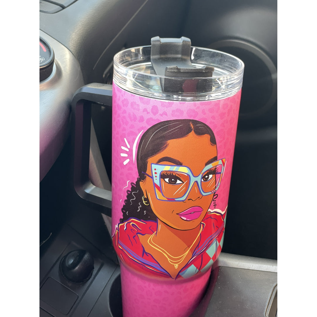 Live Life in Color by Madeleine Wood: African American Tumbler with Handle (Lifestyle) - A pink insulated tumbler with a clear lid and handle, featuring a cartoon illustration of a woman with glasses, placed in a car cup holder.
