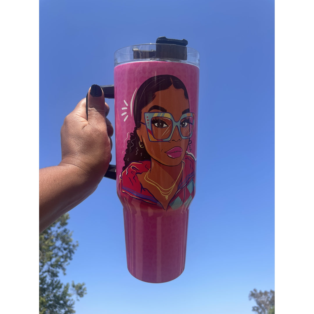 Live Life in Color by Madeleine Wood: African American Tumbler with Handle (Lifestyle) - A hand holds a pink travel tumbler with a clear lid and black handle against a bright blue sky. The tumbler features a colorful cartoon-style portrait of a woman wearing glasses.