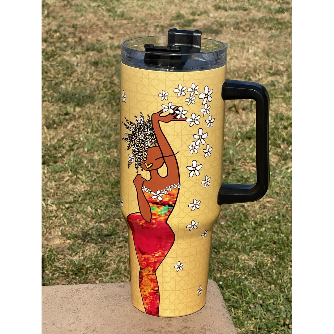 Living My Blessed Life by Kiwi McDowell: African American Tumbler with Long Handle (Lifestyle) - A handled travel tumbler with a black handle and lid, featuring a yellow background with a graphic of a dancing woman in a red dress and white flowers, set outdoors on a concrete surface with grass behind it.