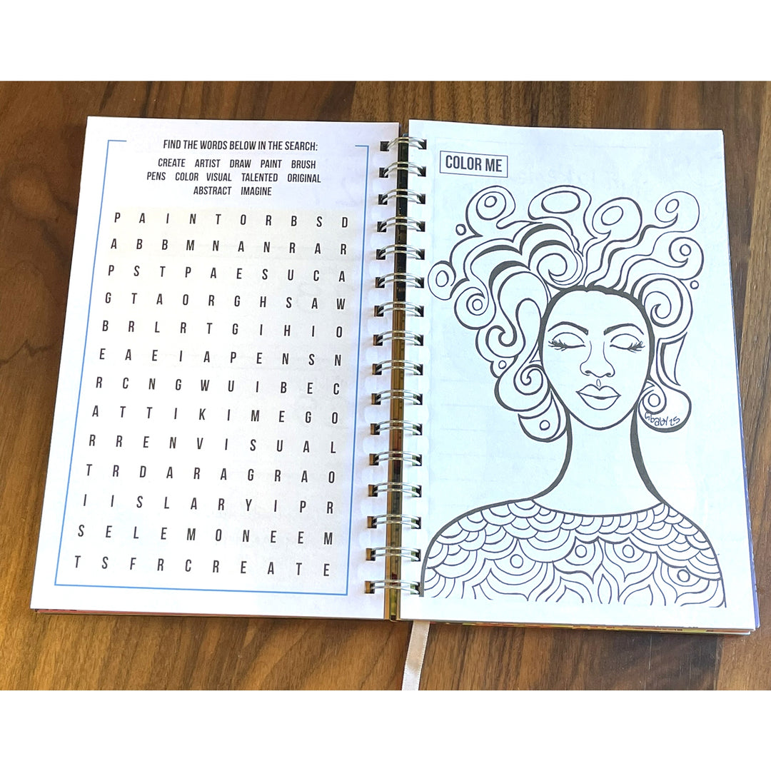 Love Yourself 2027 Weekly Inspirational Planner by Sylvia "Gbaby" Cohen (Word Search) - An open spiral-bound notebook or activity book lying on a wooden surface, showing a word search page on the left and a black-and-white line-art portrait page on the right with the title 'COLOR ME'.