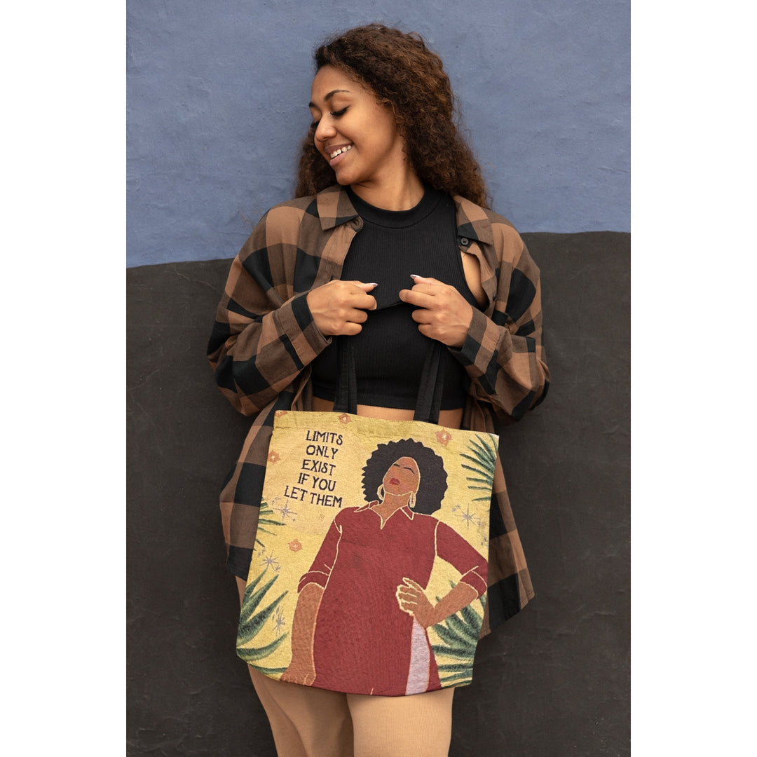 No Limits: African American Woven Tote Bag by Janine Robinson (Lifestyle 3) - Woman holding a tote bag with a graphic design of a woman with an afro and text.
