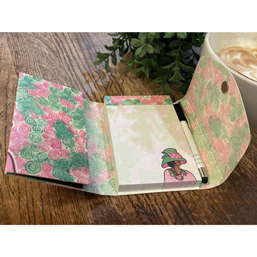 Poised for Perfection (Alpha Kappa Alpha) Stylus Purse Pal by Pamela Hills (Interior) - Floral notebook with a pen on a wooden surface next to a plant and cup of coffee.