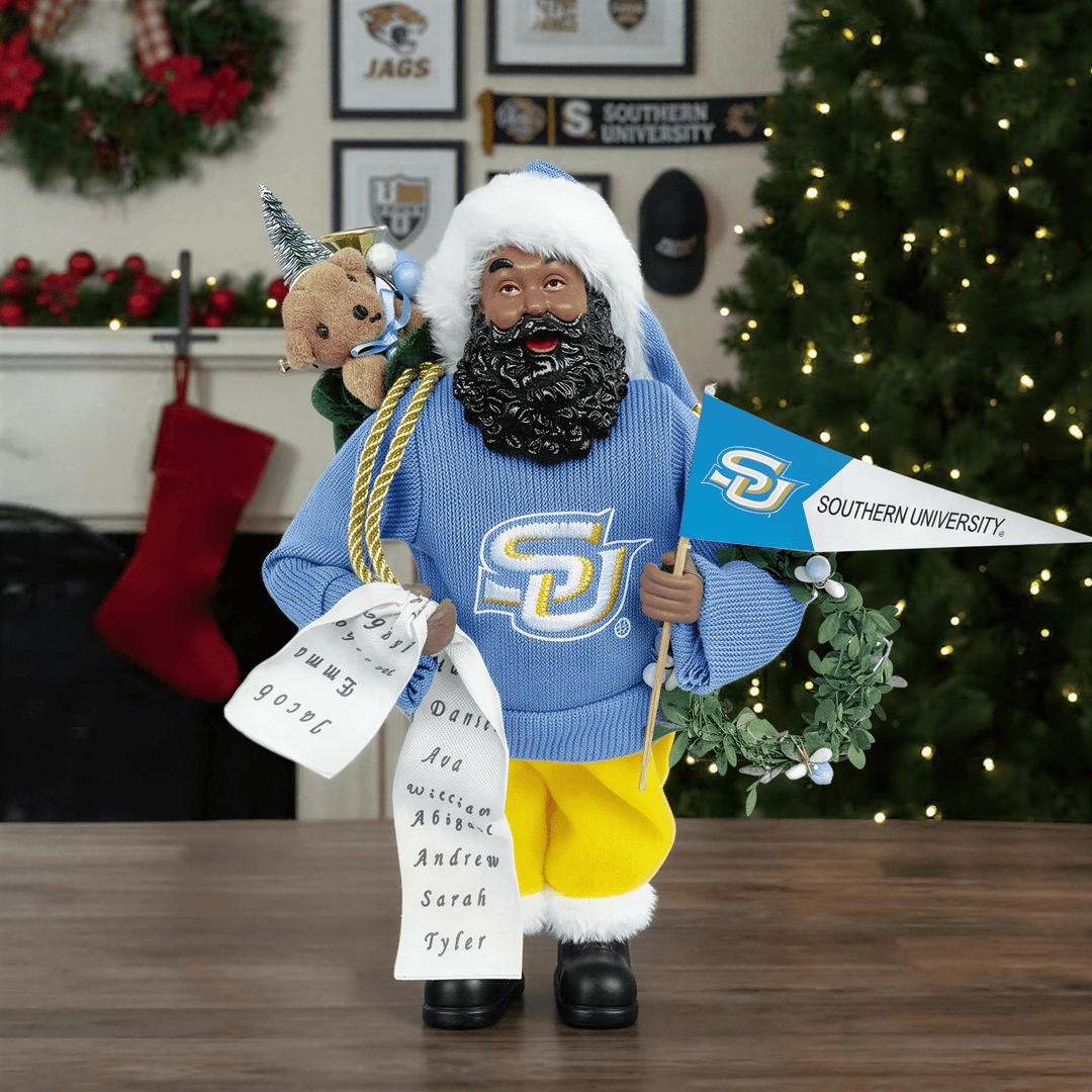Southern University Jaguars: HBCU Proud African American Santa Claus Figurine (Lifestyle) - Figurine in a blue sweater with a Southern University flag, standing in front of a decorated Christmas tree and fireplace.