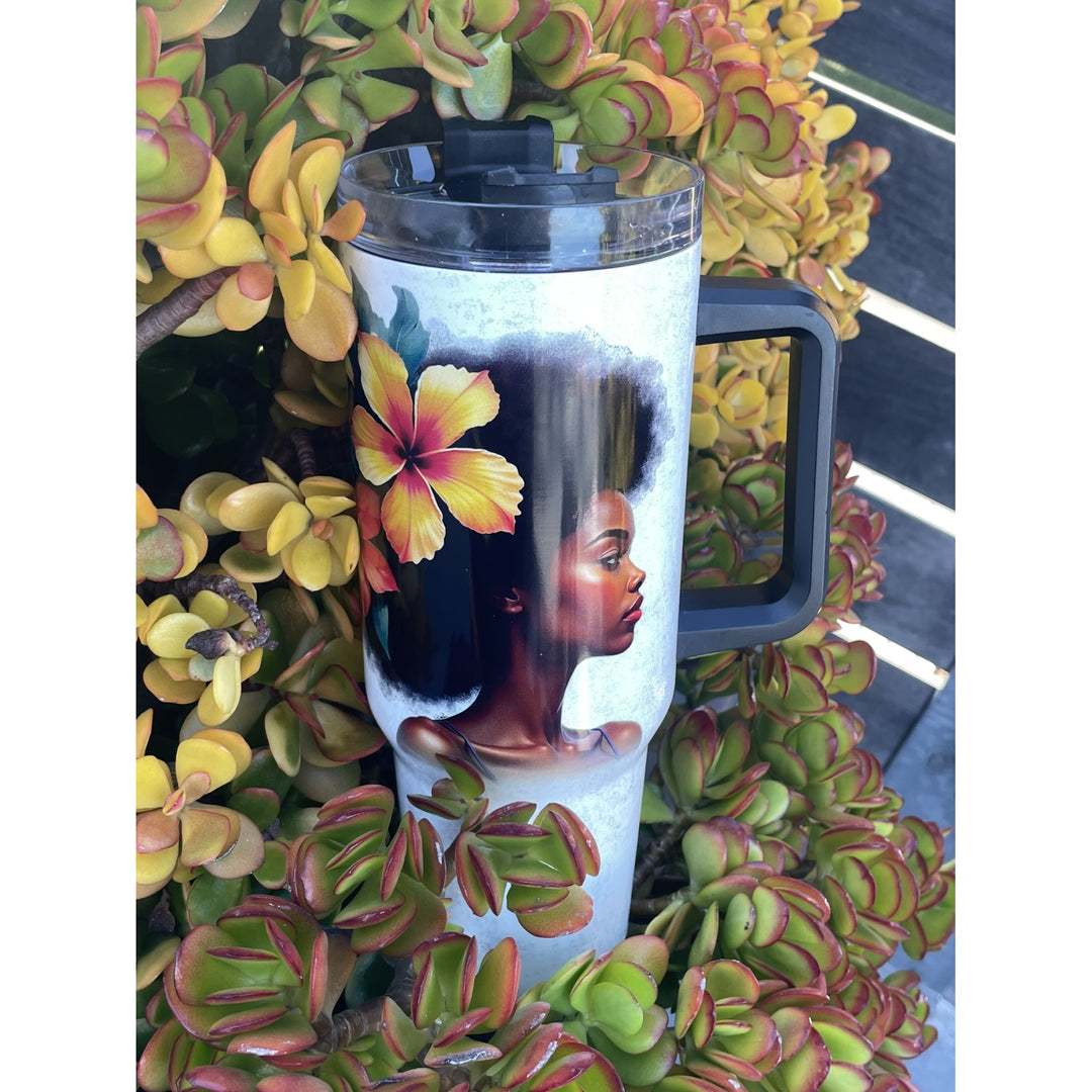 Strong and Special: African American Religious/Faith Tumbler with Handle (Lifestyle) - A handled travel tumbler with a clear lid, featuring a printed portrait of a Black woman with an afro and a large hibiscus flower in her hair, surrounded by green and yellow succulent plants.