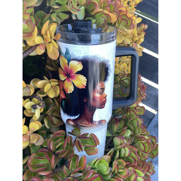 Strong and Special: African American Religious/Faith Tumbler with Handle (Lifestyle) - A handled travel tumbler with a clear lid, featuring a printed portrait of a Black woman with an afro and a large hibiscus flower in her hair, surrounded by green and yellow succulent plants.