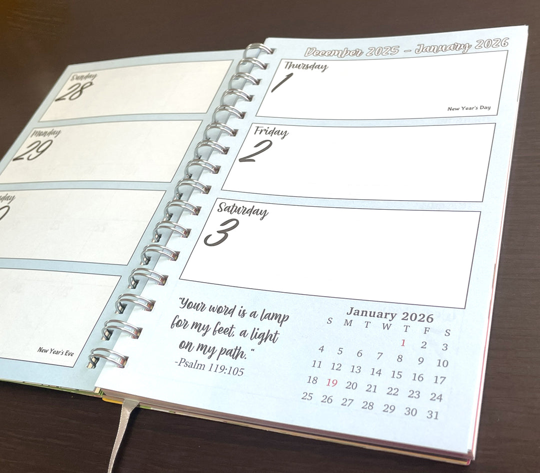 I Am Radiant by Syliva "Gbaby" Cohen: 2026 African American Weekly Inspirational Planner (Daily View) - Open spiral-bound planner showing December 2025 to January 2026 with a quote on a wooden surface.