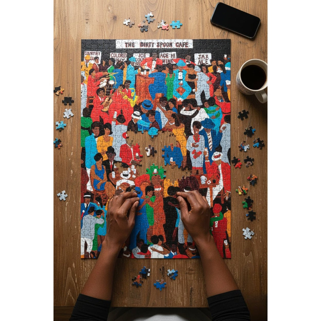 The Dirty Spoon Cafe by Winfred Rembert: African American Jigsaw Puzzle (Lifestyle) - Person assembling a puzzle of a crowded scene on a wooden table with a phone and coffee cup.