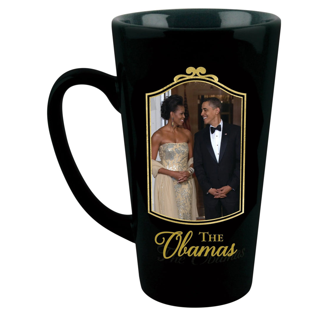 Class and Dignity: The Obamas Commemorative Ceramic Latte Mug (Front) - A black ceramic mug featuring a printed photo of Barack and Michelle Obama inside a gold frame, with 'The Obamas' written in gold script below the photo.