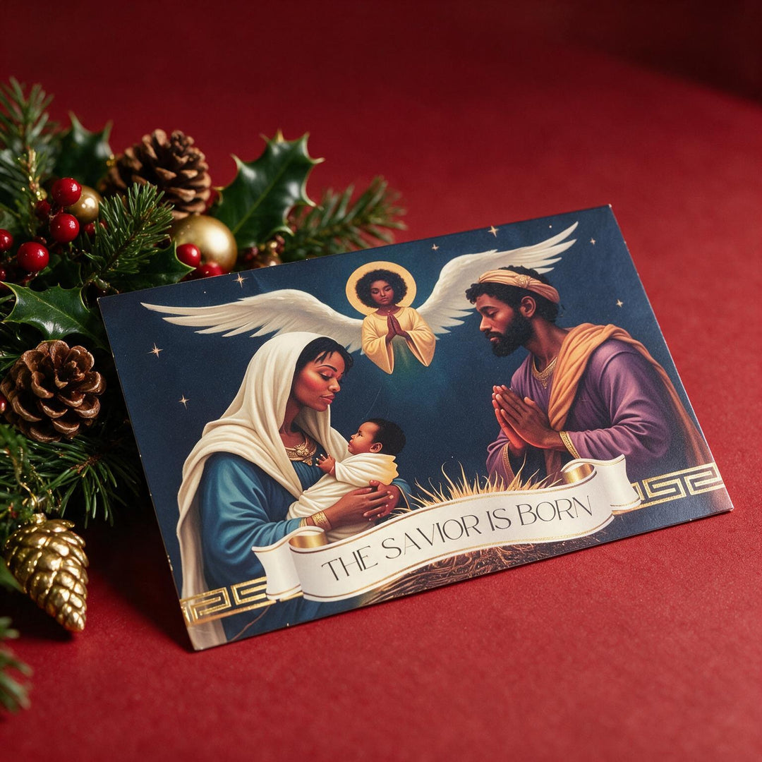 The Savior Is Born: African American  Christmas Card Box Set by Janine Kai Robinson (Lifestyle 4) - A Christmas card featuring the Holy Family and an angel, styled on a red background with pine branches, pinecones, and holly.
