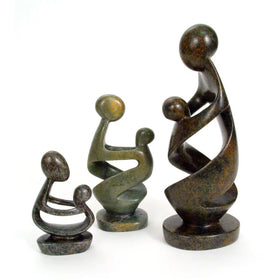Ukama: Hand Carved Mother and Child Shona Sculpture (Main) - Three abstract family figurines in dark bronze and olive green patinated metal, depicting a mother, father, and child, arranged by size on a white background.