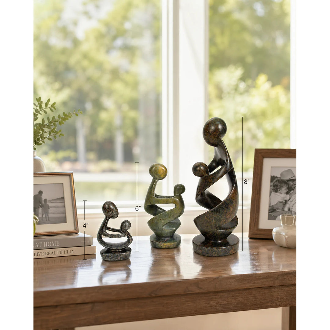 Ukama: Hand Carved Mother and Child Shona Sculpture (Sizing Guide) - Three abstract mother-and-child sculptures in dark bronze and green patina finishes displayed on a wooden table in a bright room, with height measurement lines overlaid on the image.