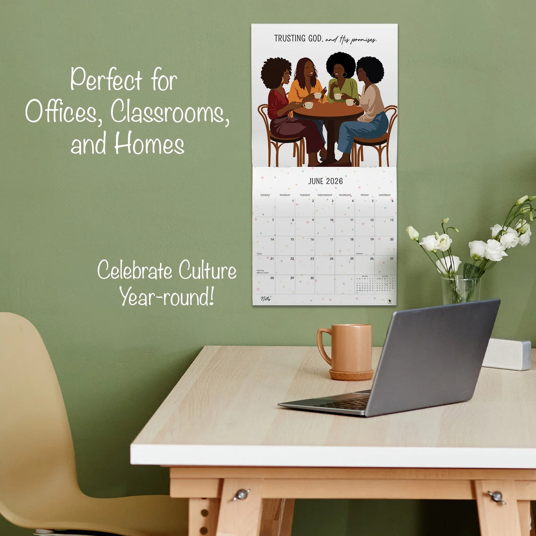 A Woman Who Walks With GOD: The Art of Nicholle Kobi 2026 Wall Calendar (Lifestyle) - Calendar on a wall above a desk with a laptop and mug, against a green background.